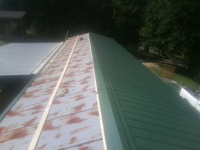 Old rusted panels beside newly installed green metal roofing — Wind Damage Roof Repair by Roofing Brothers in Petaluma