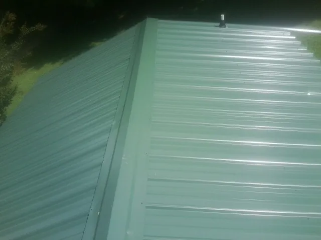 New green metal panels meeting at the ridge of a roof — Flat Roof Repair work by our crew in Petaluma