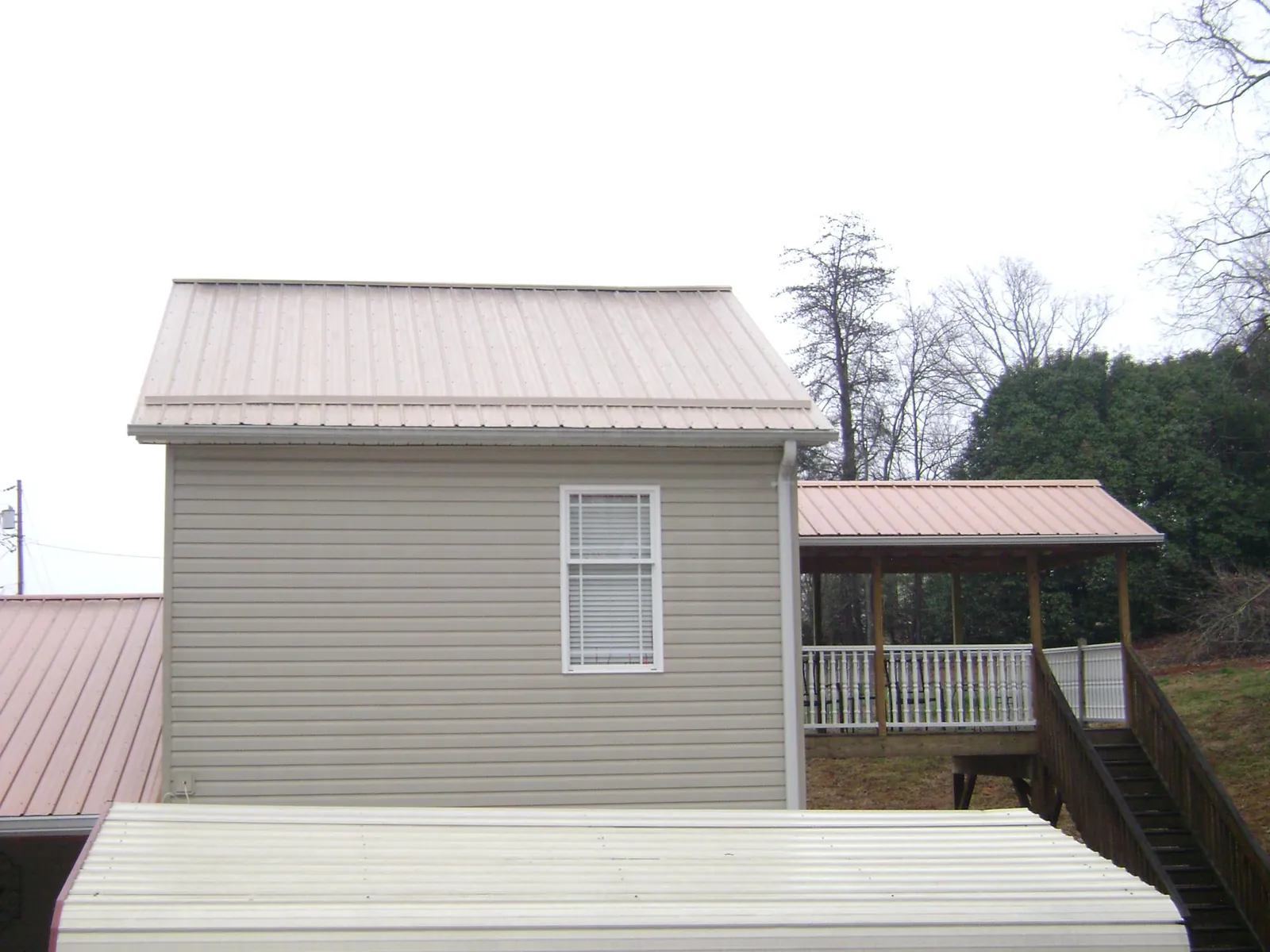 Tan metal roofs on a two story addition and attached porch, from a Roof Replacement job in Petaluma